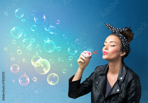 Tableau sur toile Pretty lady blowing colorful bubbles on blue background
