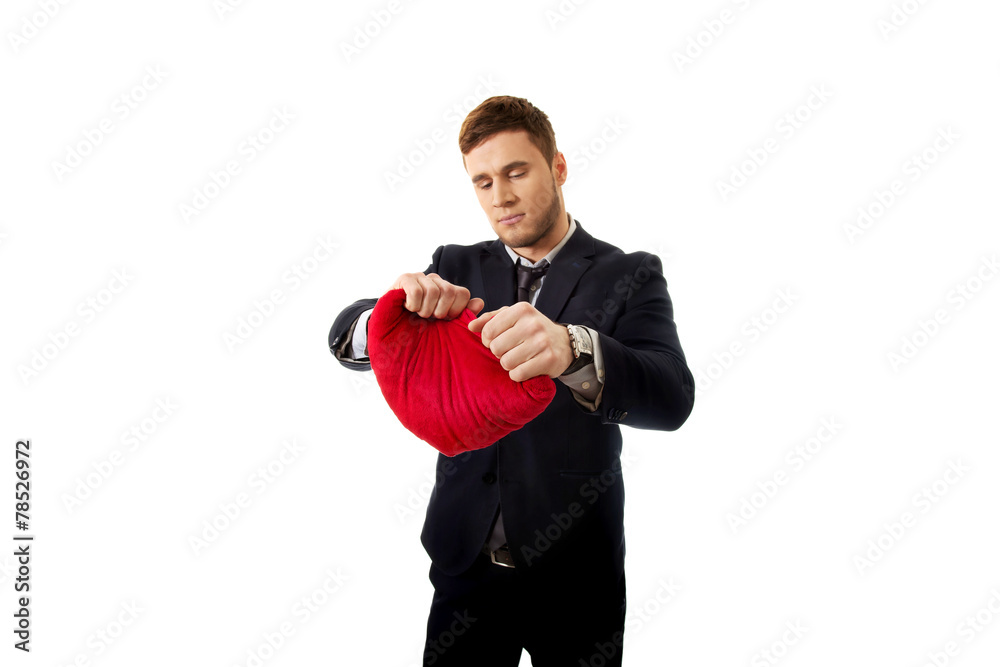 Businessman tears heart shaped pillow. Businessman tears heart shaped pillow.