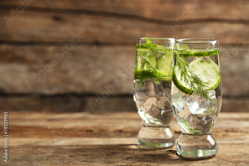 Glasses with fresh organic cucumber water on wooden table
