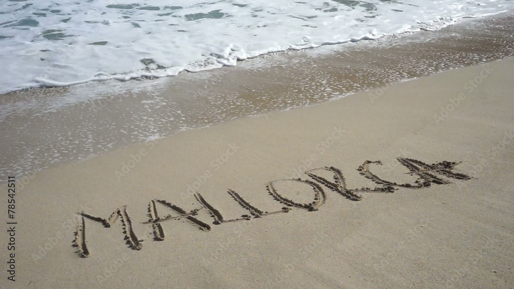 Wort MALLORCA am Sandstrand wird von Wellen weggespült