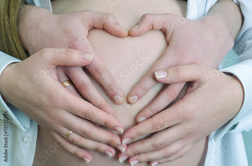 Four hands on a pregnant belly