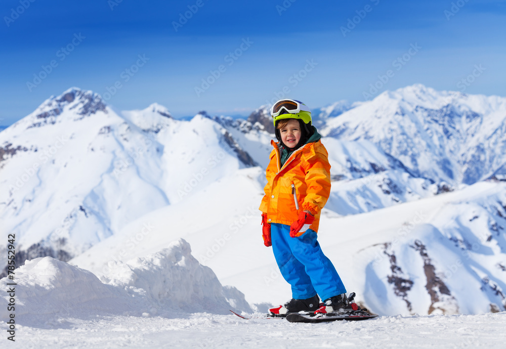 Smiling cute boy wearing ski mask, helmet skiing