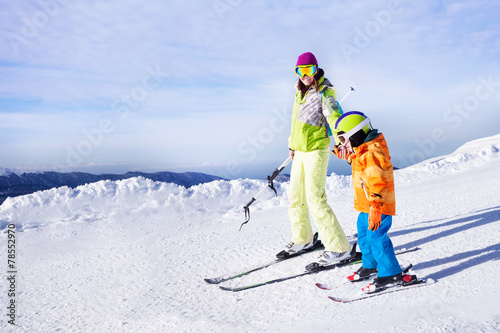 Teaching little boy to ski going holding hand