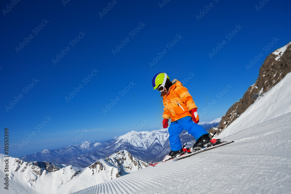 Brave small boy skiing alone on mountain slope