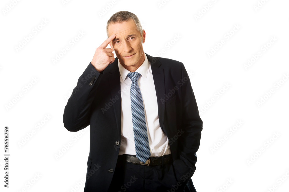Businessman gesturing with finger against temple Businessman gesturing with finger against temple