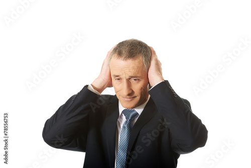 Portrait of tired man covering ears with hands