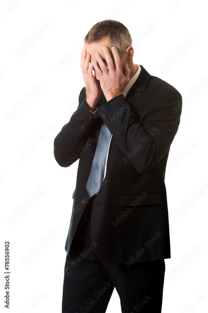 Stressed businessman covering his face with hands Stressed businessman covering his face with hands