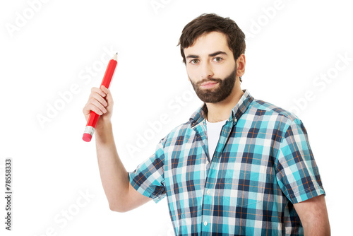 Young man holding big red pencil.