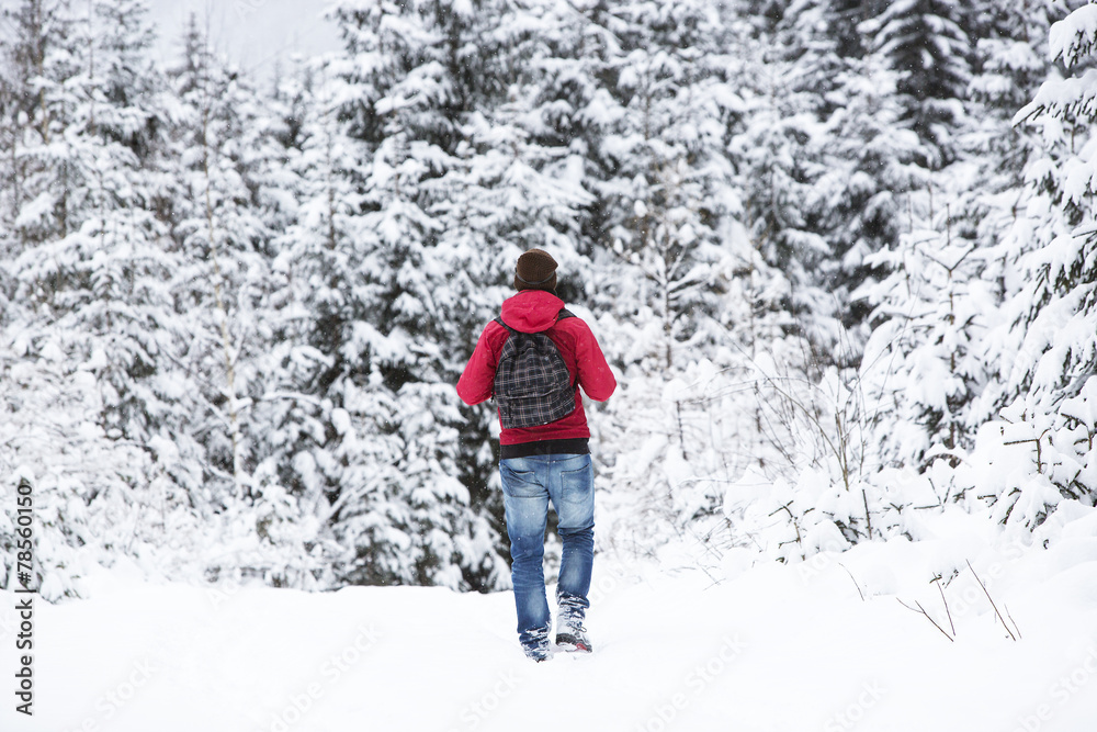 Young man hiking in wintry forest landscape