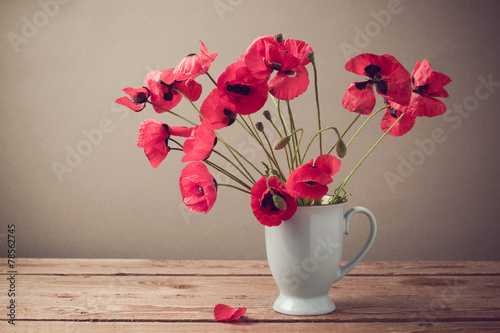 Poppies in cup on wooden table