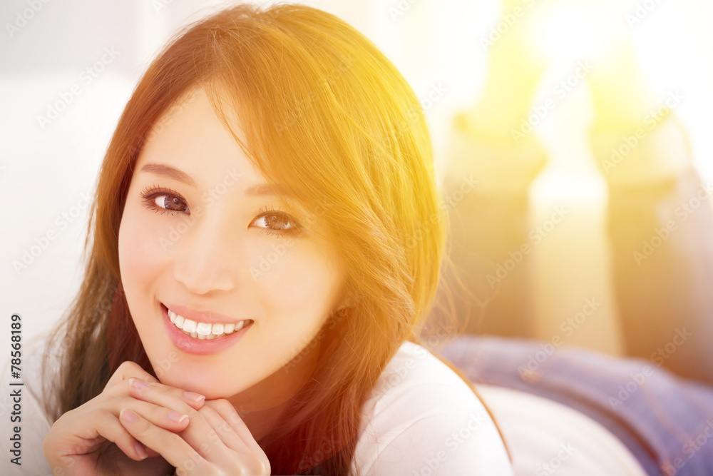 smiling Young woman lying on the sofa with sunlight background smiling Young woman lying on the sofa with sunlight background