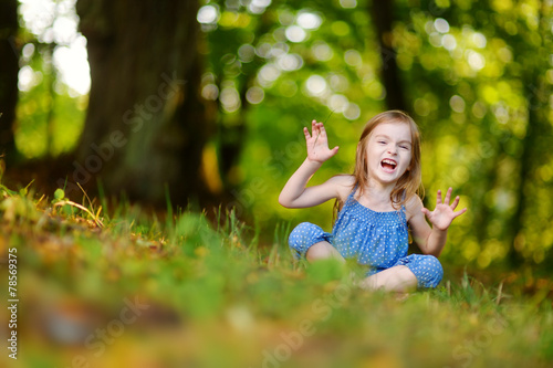 Cute little girl sitting on the grass on summer