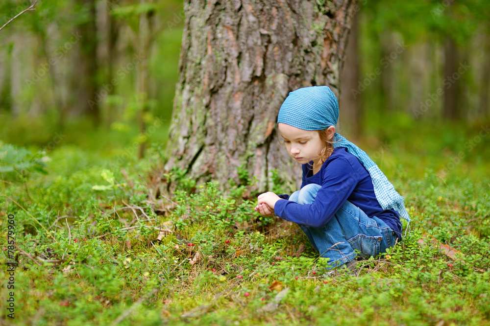 Adorable girl picking foxberries in the forest Adorable girl picking foxberries in the forest