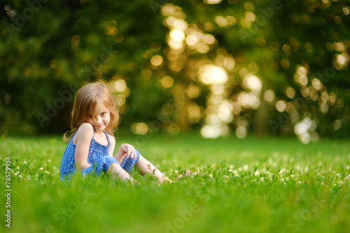 Cute little girl sitting on the grass on summer