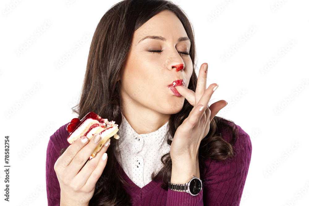 Beautiful stained girl eating cake and licks her fingers Beautiful stained girl eating cake and licks her fingers