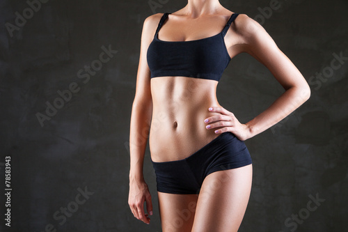 Slim woman's body  over dark grey background © julenochek