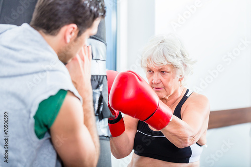 Seniorin Frau mit Trainer beim Boxen