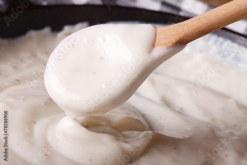 bechamel sauce with a wooden spoon close-up, horizontal