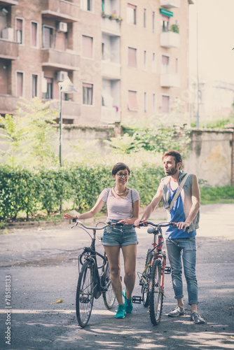 couple of friends young man and woman riding bike