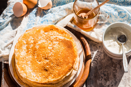 many subtle sweet pancakes with honey and sour cream
