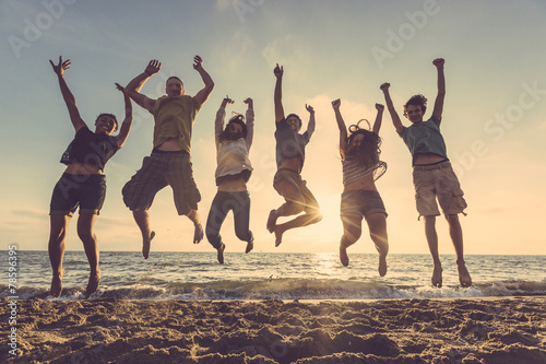 Multiracial group of people jumping at beach