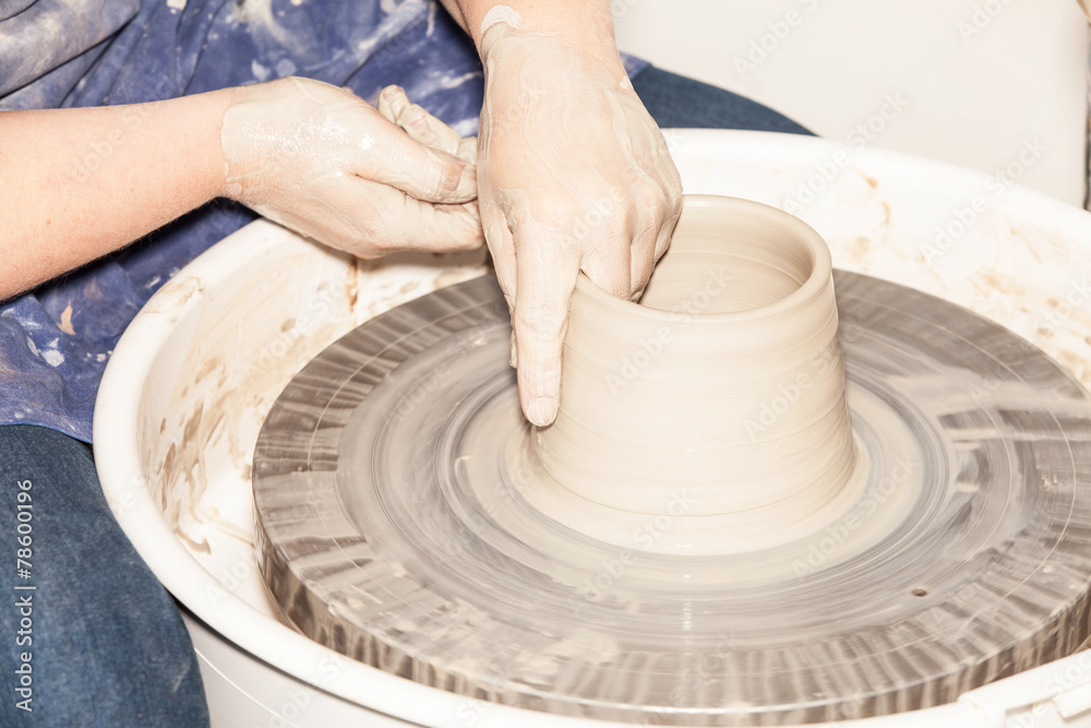 Female Potter creating a earthen jar on a Potter's wheel Female Potter creating a earthen jar on a Potter's wheel