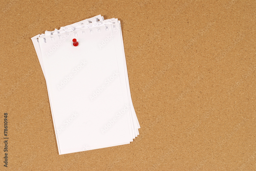 Untidy torn notepaper pinned to a cork bulletin board background Untidy torn notepaper pinned to a cork bulletin board background