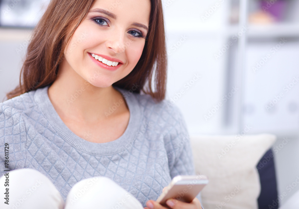 Pretty girl using her smartphone on  couch at home in the living