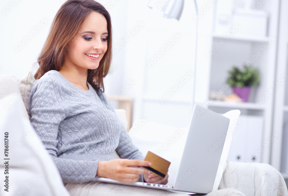 Fototapeta premium Beautiful smiling woman with laptop and a credit card