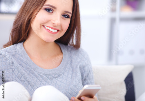 Pretty girl using her smartphone on couch at home in the living