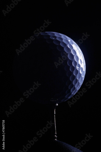 A golf ball on a tee, in dramatic black and white
