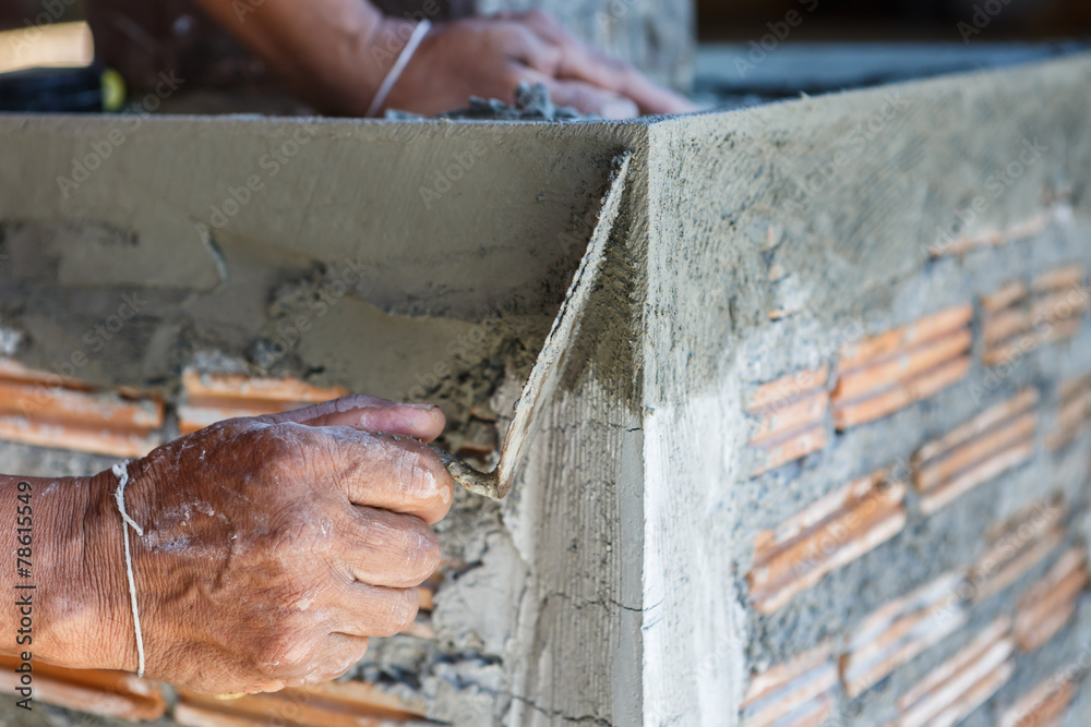 plasterer concrete worker at wall of house construction