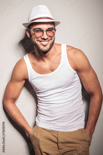 Smiling young fashion man leaning on a white wall