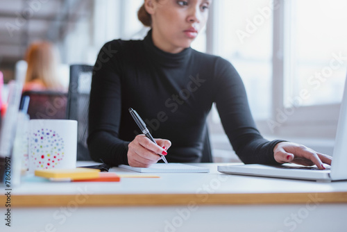 Woman taking notes from laptop