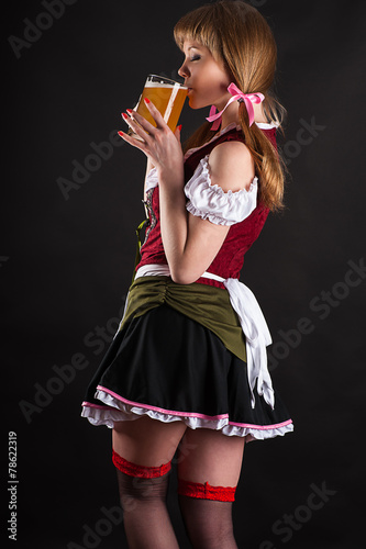 sexy woman Oktoberfest drinks beer isolated on black
