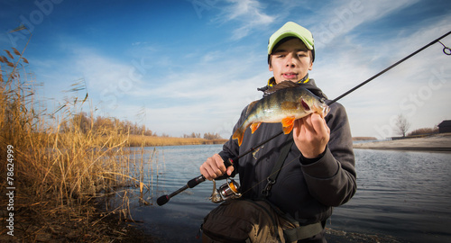 Happy angler with perch fishing trophy
