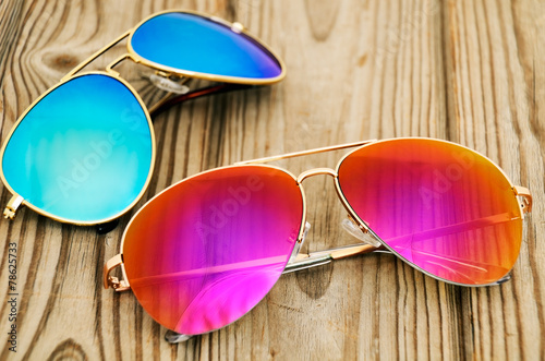 Fotografie two colored sunglasses on the wooden background