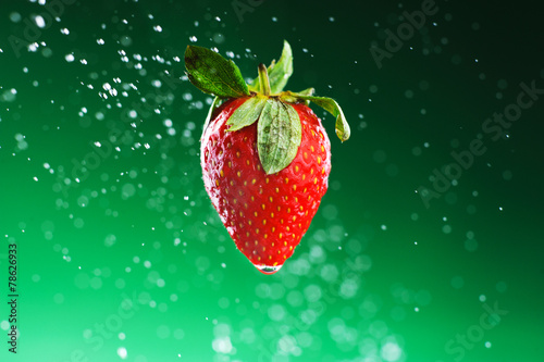 Strawberry on a green background with drops of water