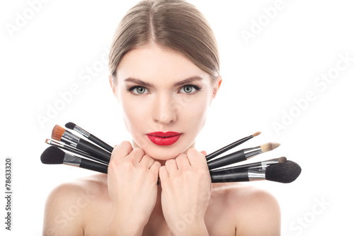 Portrait of beautiful woman with make-up brushes near face