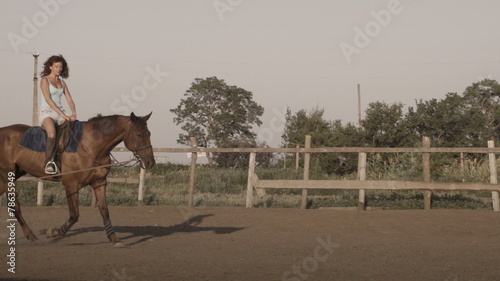 Young woman riding a horse on a lunging rein