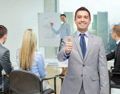 happy businessman in suit showing thumbs up