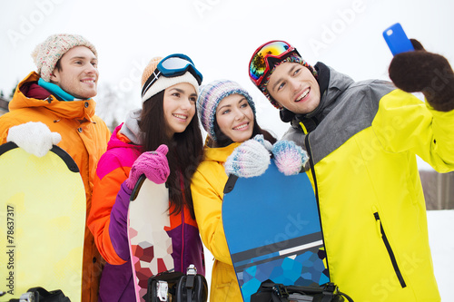 happy friends with snowboards and smartphone