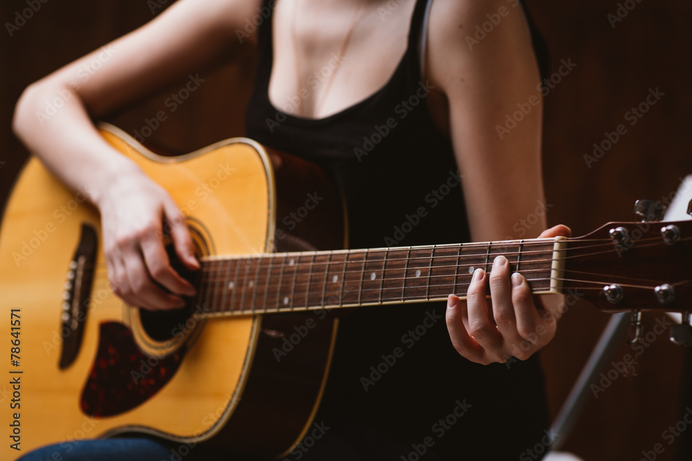 woman's hands playing acoustic guitar, close up