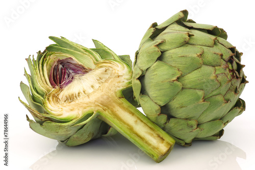 one whole and cut artichoke on a white background
