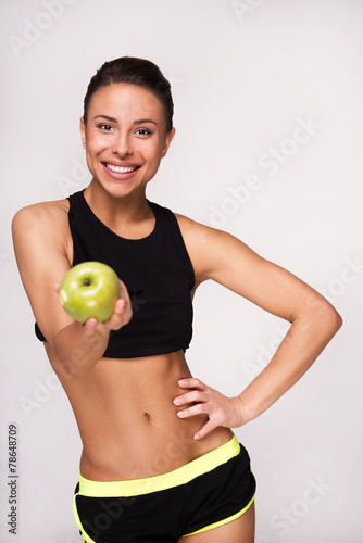 Sporty mixed race woman showing an apple to camera
