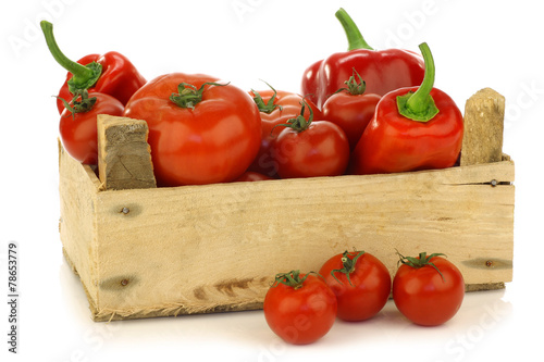red sweet peppers and tomatoes in a wooden crate