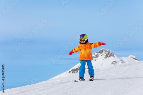 Boy with ski mask and arms apart skiing in winter