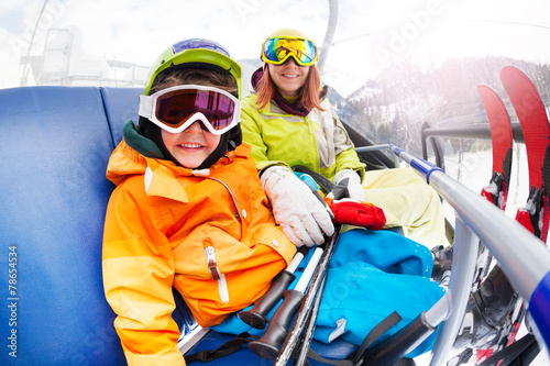 Happy little boy with mom, mountain ski chair lift