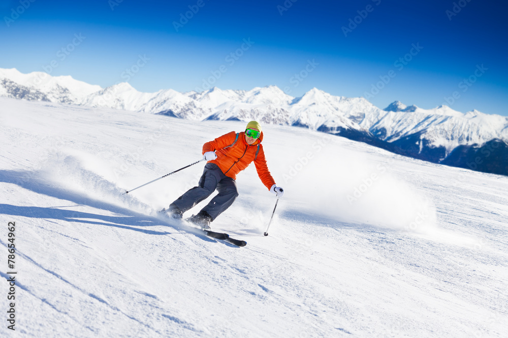 Skier in mask slides fast while skiing from slope