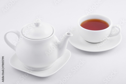 white tea cup with tea and white teapot on white background